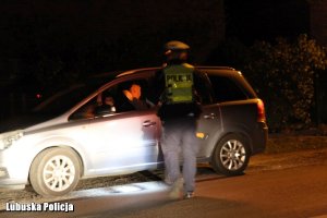 Policjant ruchu drogowego stojący prze pojeździe w nocy.