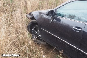 Uszkodzony przód czarnego samochodu osobowego w polu.