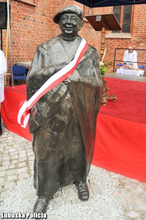 Pomnik z biało - czerwoną szarfą.