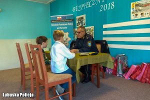 Strażnik miejski rozmawiający z przedszkolakami przy stoliku