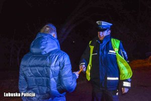 Policjant w porze nocnej wręcza odblaski mężczyźnie