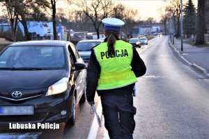 policjantka idzie wzdłuż drogi do pojazdów