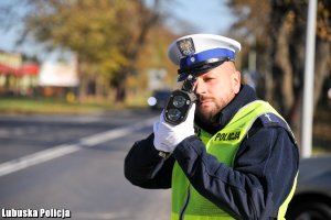 Policjant ruchu drogowego na drodze mierzy prędkość