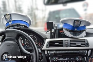 Policyjne czapki ruchu drogowego na pulpicie radiowozu