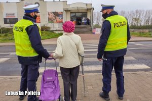 policjanci przeprowadzają seniorkę przez przejście dla pieszych