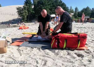 Strażacy wykonują pokaz resuscytacji krążeniowo - oddechowej na plaży.