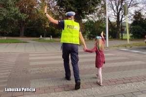 policjantka przeprowadza dziewczynkę przez drogę