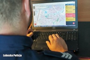 Policjant siedzący przed komputerem sprawdzający Krajową Mapę Zagrożeń Bezpieczeństwa