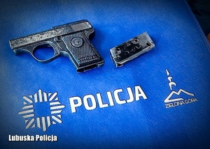 Zabytkowy pistolet na niebieskiej torbie z napisem Policja.