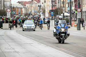 Policyjny motocykl prowadzi kolumnę rowerzystów