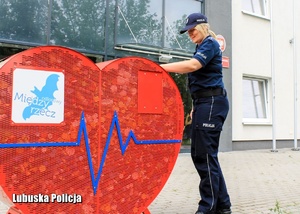 Policjantka przy pojemniku metalowym w kształcie serca.
