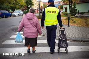 Policjant pomaga starszej pani przejść przez przejście dla pieszych