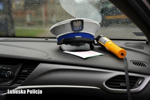 Czapka policjanta ruchu drogowego i urządzenie do badania stanu trzeźwości we wnętrzu radiowozu.