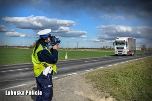 Policjant drogówki sprawdza prędkość pojazdu ciężarowego na drodze.