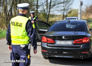 Policjanci drogówki podczas kontroli drogowej pojazdu osobowego.