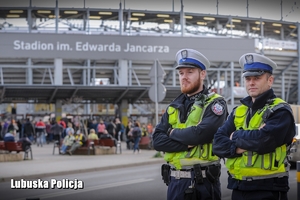 policjanci stoją przy stadionie żużlowym i obserwują zachowanie kibiców