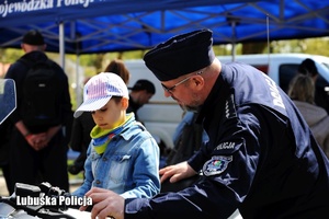 Policjant obok chłopca siedzącego na motocyklu.