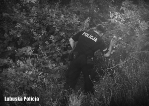 Czarno - białe zdjęcie przedstawiające policjanta, podczas poszukiwań.