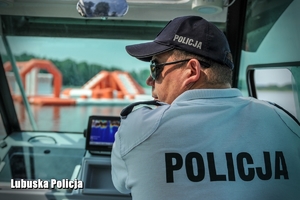Policjant podczas patrolu jeziora na motorówce.