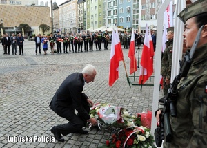 Starszy mężczyzna składa kwiaty przed Białym Krzyżem &quot;Solidarności&quot;.