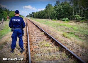Policjant stojący przy torach kolejowych.