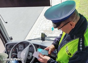 Policjant drogówki sprawdza dokumenty kierowcy autokaru.