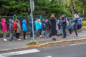 Dzieci oraz policjantka z nauczycielkami na chodniku.