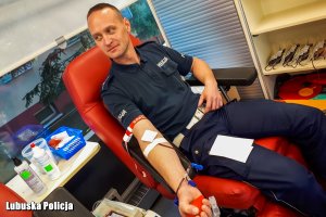Policjant oddaje krew w krwiobusie.