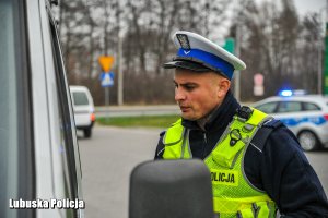 Policjant ruchu drogowego przy kontrolowanym samochodzie