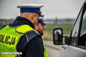 Policjanci ruchu drogowego przy kontrolowanym samochodzie