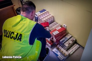 Policjant na tle zabezpieczonych papierosów bez polskich znaków skarbowych akcyzy