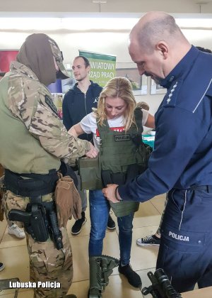 antyterrorysta i policjant ubierają dziewczynkę w kamizelkę