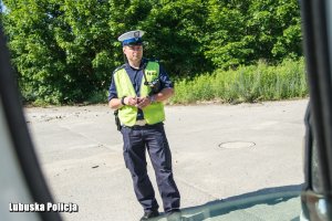 policjant sprawdza stan techniczny kontrolowanego auta