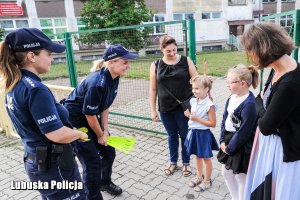 Policjantki wręczają dzieciom elementy odblaskowe.