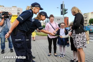Policjantki wręczają dzieciom elementy odblaskowe.