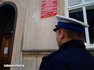 Policjant ruchu drogowego przy budynku powiatowego inspektoratu sanitarnego