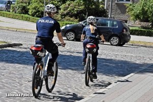 policjantka i policjant w patrolu rowerowym legitymują osoby