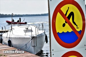 Znak zakaz skoków do wody, jacht i w tle patrol policji wodnej