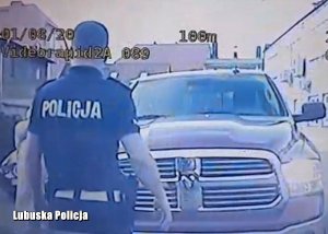 Policjant przed  kontrolowanym samochodem