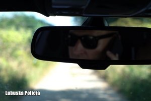 Oszust w ciemnych okularach w lusterku wstecznym auta