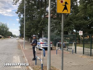 policjant kontroluje oznakowanie w rejonie szkoły
