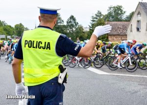 Policjant kieruje ruchem podczas kolarskiego wyścigu.