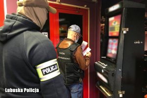 Policjant i funkcjonariusz Krajowej Administracji Skarbowej podczas zabezpieczanie automatów do gier.