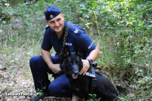 Policjant z przewodnikiem psa w lesie.