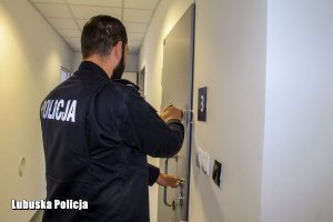 Policjant zamyka drzwi pomieszczenia dla osób zatrzymanych