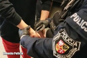 policjant zakłada kajdanki podejrzanej