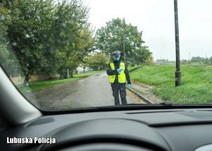 Policjant ruchu drogowego sprawdza stan techniczny auta zatrzymanego do kontroli