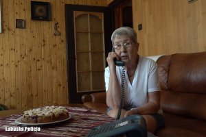 Starsza kobieta siedzi na kanapie i rozmawia przez telefon.