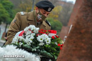 Generał Wojska Polskiego trzymający wiązankę kwiatów.