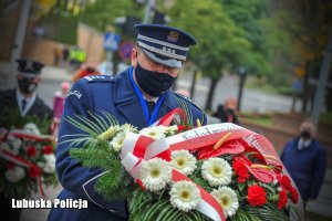 Komendant Wojewódzki Policji trzymający wiązankę kwiatów.